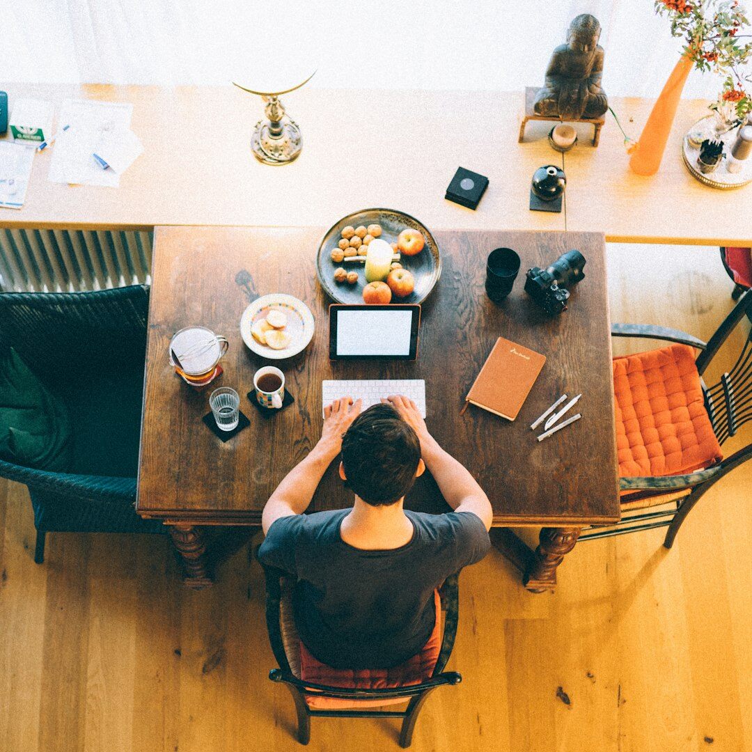 Croatian male author's hands writing notes in a notebook beside a laptop at a wooden desk